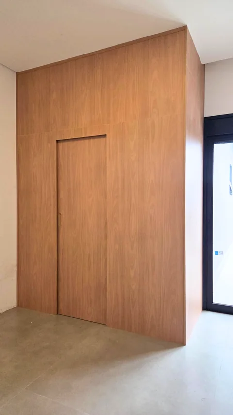 Parede revestida em painéis amadeirados com uma porta integrada ao desenho.